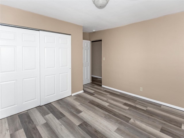 unfurnished bedroom with dark wood-type flooring and a closet