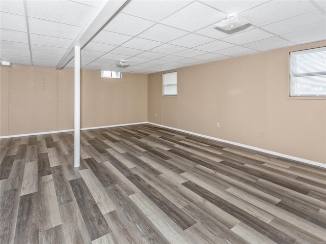 basement featuring a drop ceiling, a wealth of natural light, and dark wood-type flooring