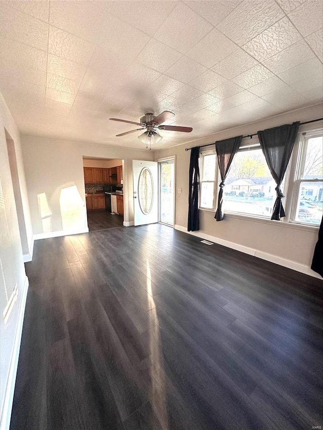 unfurnished living room featuring dark wood-type flooring, ceiling fan, and a healthy amount of sunlight