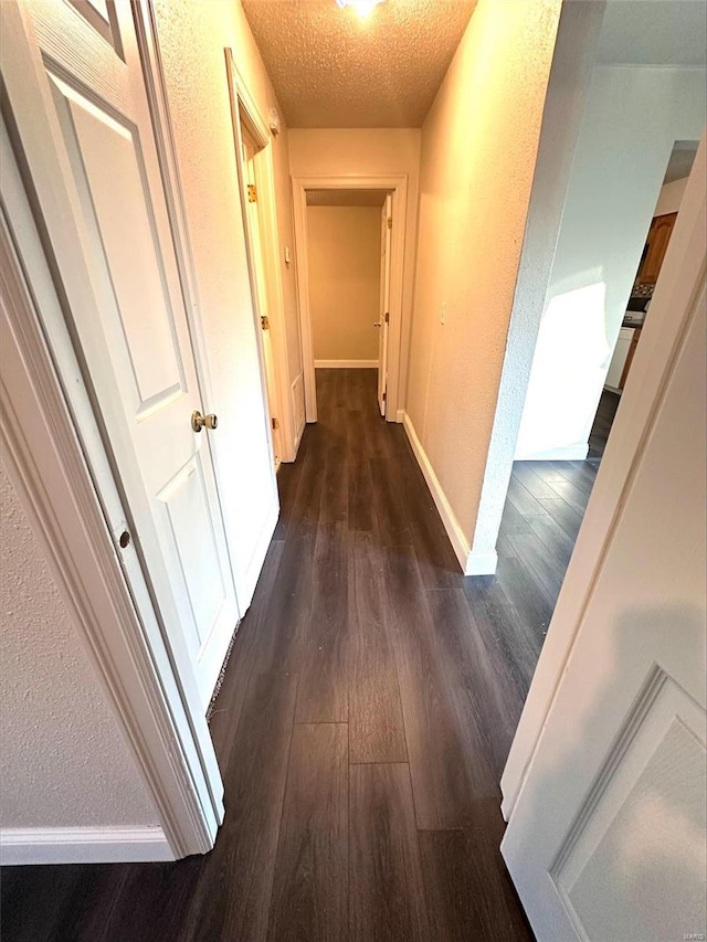 corridor featuring dark wood-type flooring and a textured ceiling