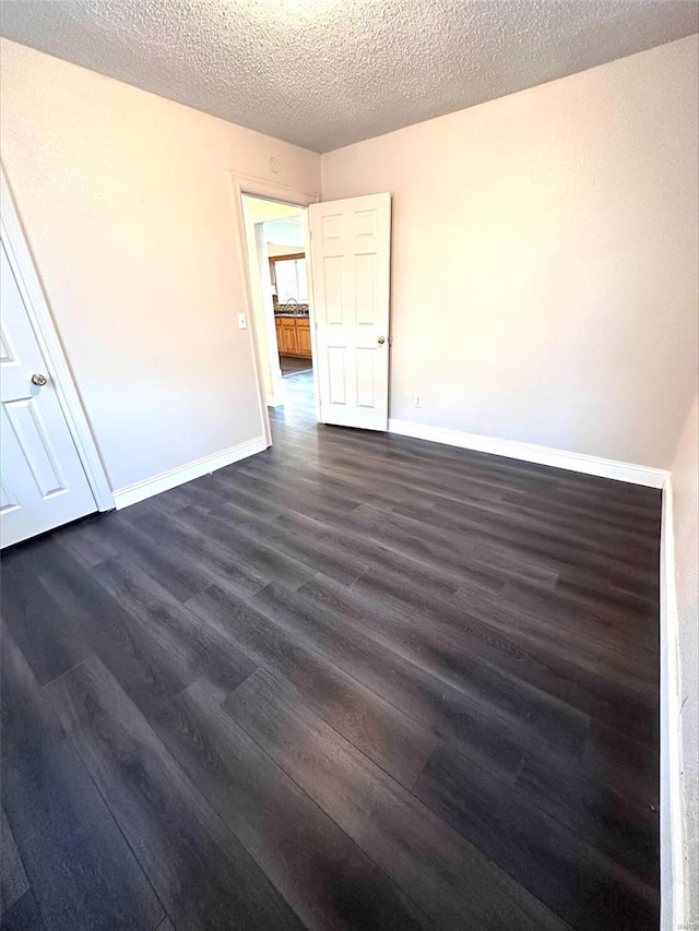 unfurnished room with dark wood-type flooring and a textured ceiling