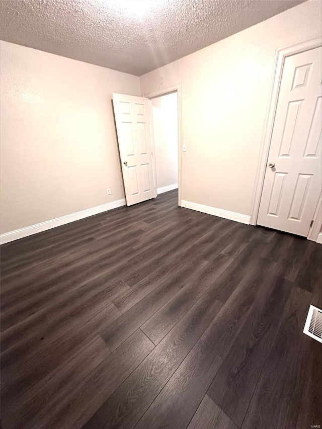 spare room with dark wood-type flooring and a textured ceiling