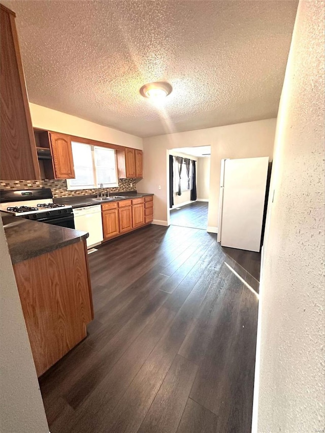 kitchen featuring dark hardwood / wood-style flooring, sink, white appliances, and a textured ceiling