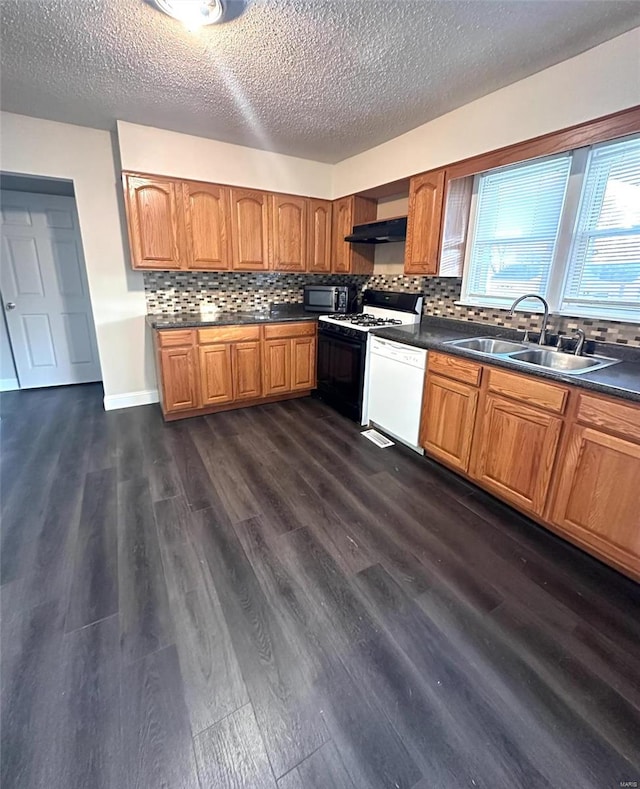 kitchen featuring dark wood-type flooring, white appliances, sink, and tasteful backsplash