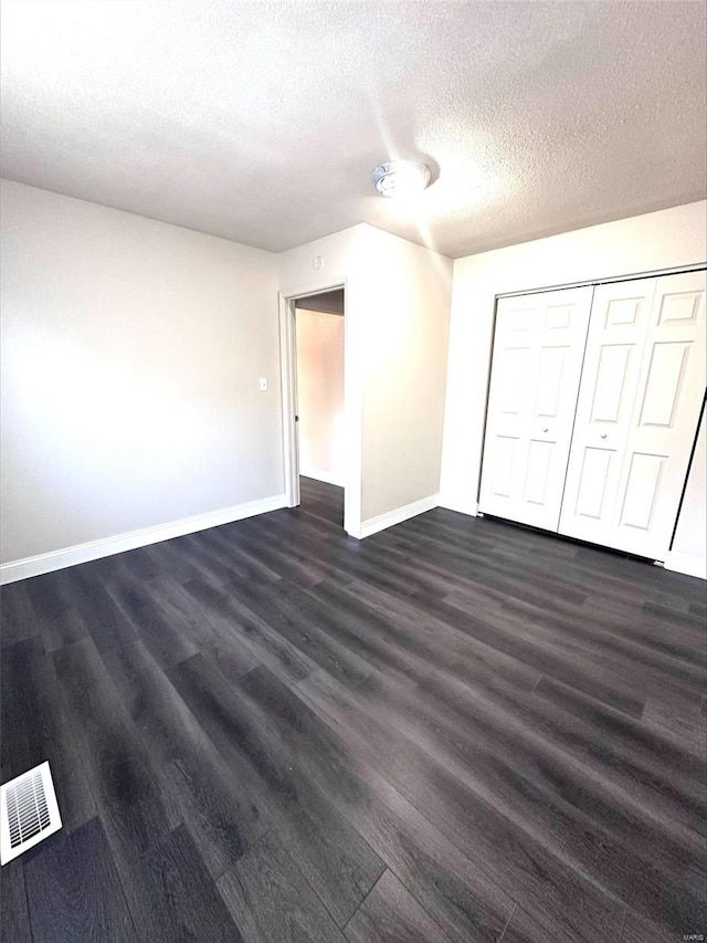 unfurnished bedroom featuring dark hardwood / wood-style flooring, a textured ceiling, and a closet