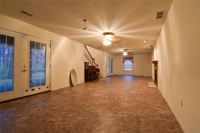 interior space with ceiling fan, french doors, and a textured ceiling