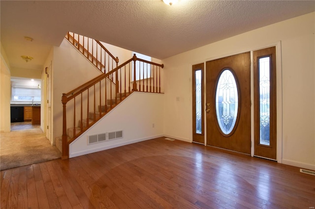 entryway with wood-type flooring and a textured ceiling