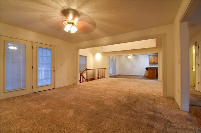 spare room with ceiling fan, light colored carpet, and a textured ceiling