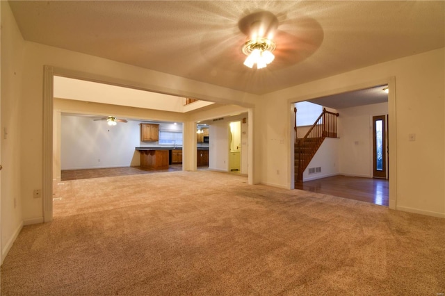 unfurnished living room with ceiling fan and light colored carpet