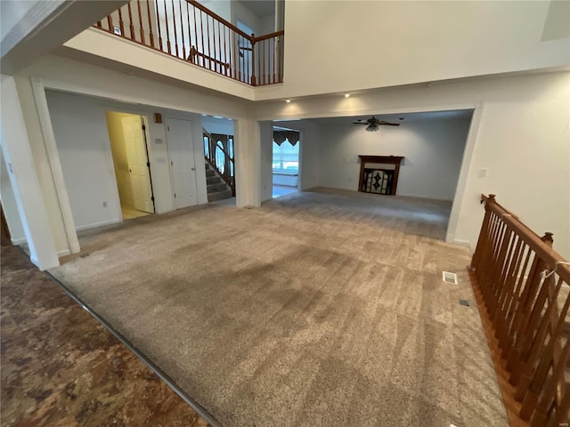 carpeted living room featuring a towering ceiling and ceiling fan