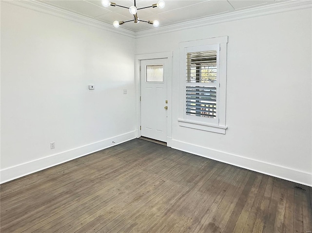 spare room featuring dark wood-type flooring, a notable chandelier, and ornamental molding