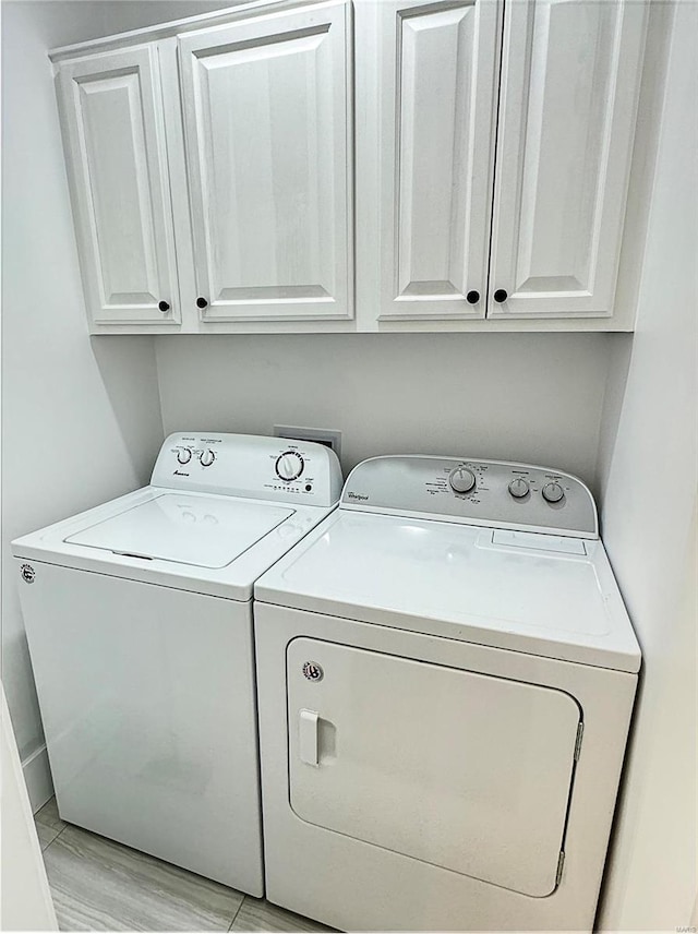 clothes washing area featuring washing machine and dryer, cabinets, and light wood-type flooring