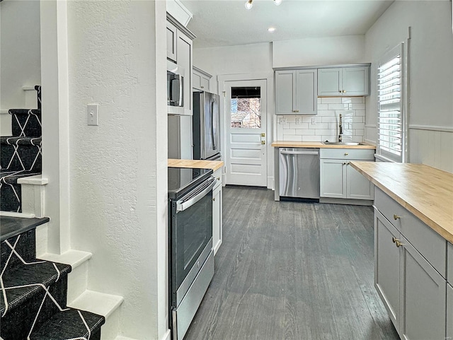 kitchen featuring dark hardwood / wood-style flooring, sink, wooden counters, and appliances with stainless steel finishes