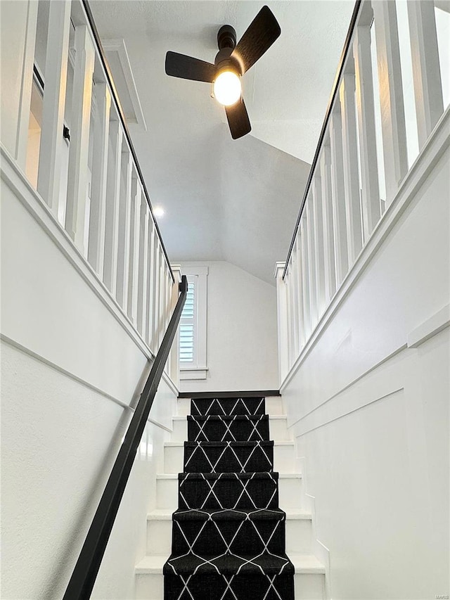 stairs featuring vaulted ceiling and ceiling fan