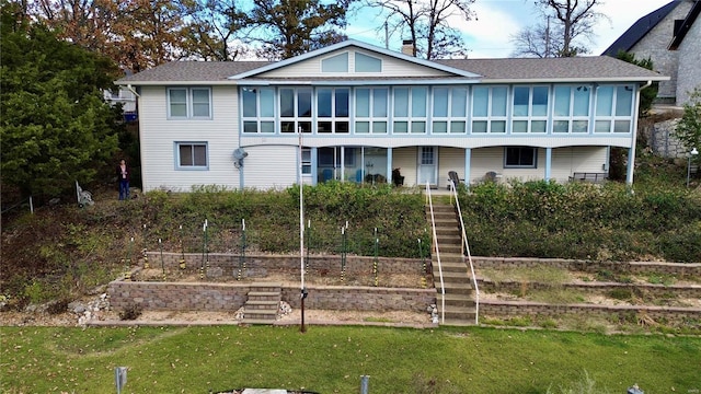 back of property featuring a sunroom and a lawn