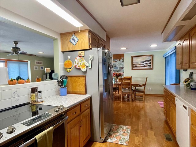 kitchen featuring light wood-type flooring, backsplash, ceiling fan, and stainless steel appliances