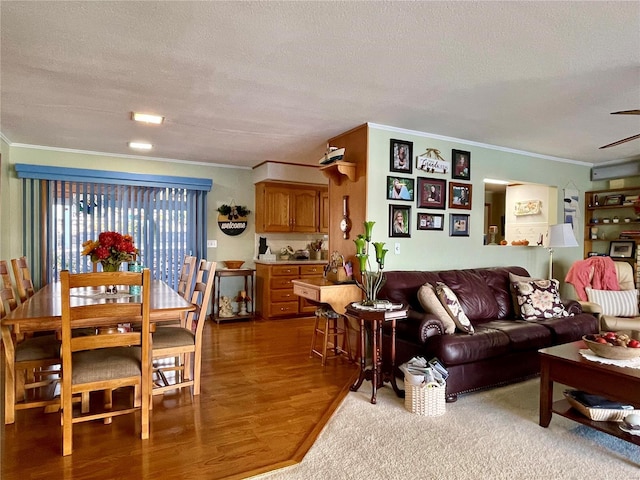 living room featuring ornamental molding, wood-type flooring, a textured ceiling, and ceiling fan