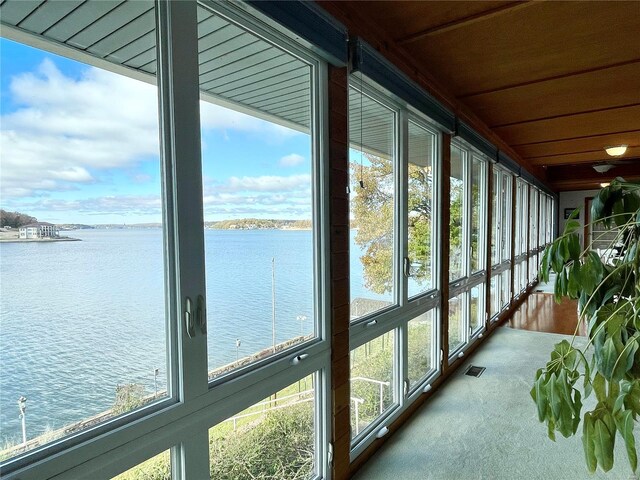 sunroom featuring wooden ceiling and a water view