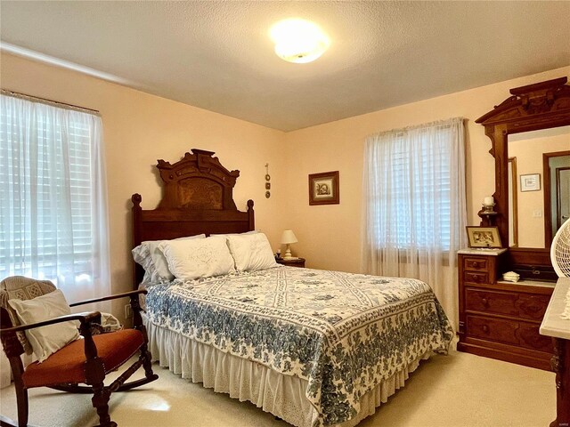 bedroom with light colored carpet and a textured ceiling