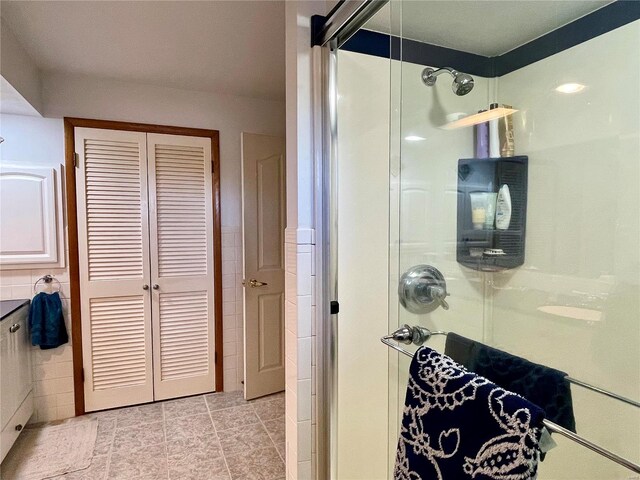 bathroom with tile walls, tile patterned flooring, and a shower with shower door