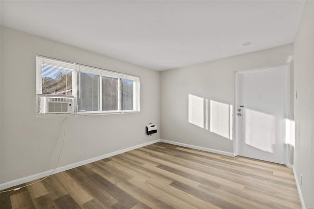 unfurnished room with light wood-type flooring, heating unit, and cooling unit