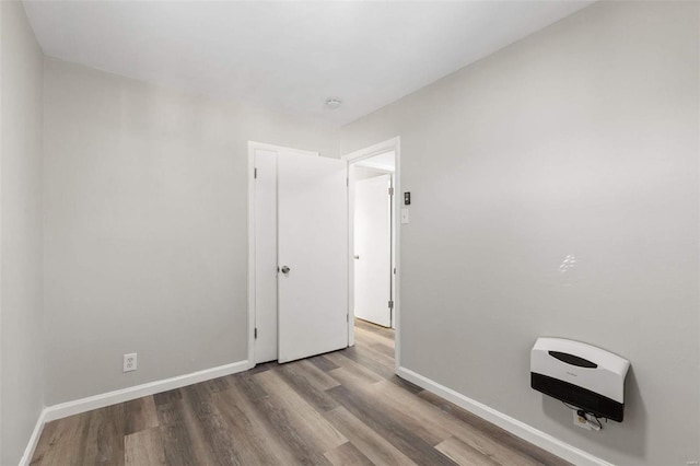 spare room with heating unit and light wood-type flooring