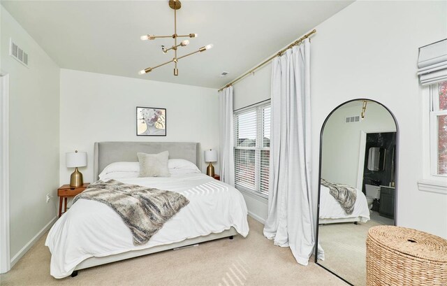 bedroom featuring light colored carpet, ensuite bath, and a notable chandelier