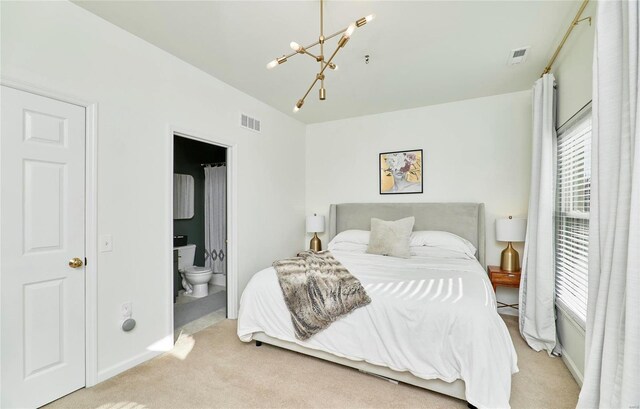 carpeted bedroom featuring ensuite bath and an inviting chandelier