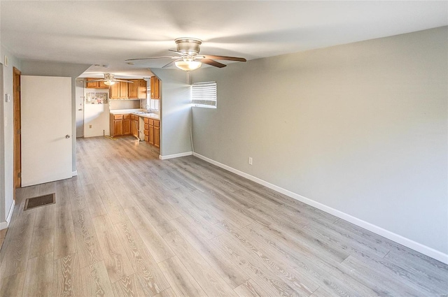 unfurnished living room with ceiling fan, light wood-type flooring, and sink