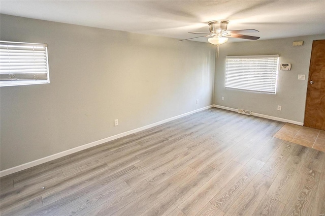 empty room with ceiling fan, a healthy amount of sunlight, and light hardwood / wood-style flooring