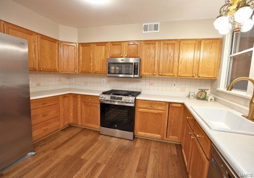 kitchen with appliances with stainless steel finishes, dark wood-type flooring, sink, backsplash, and hanging light fixtures