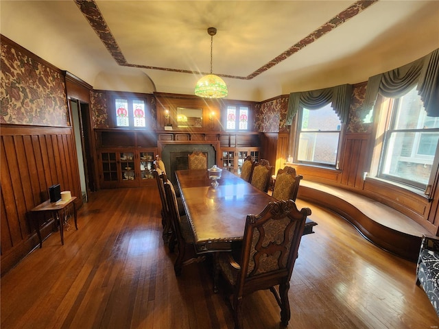 dining area with wood-type flooring, an inviting chandelier, and wooden walls