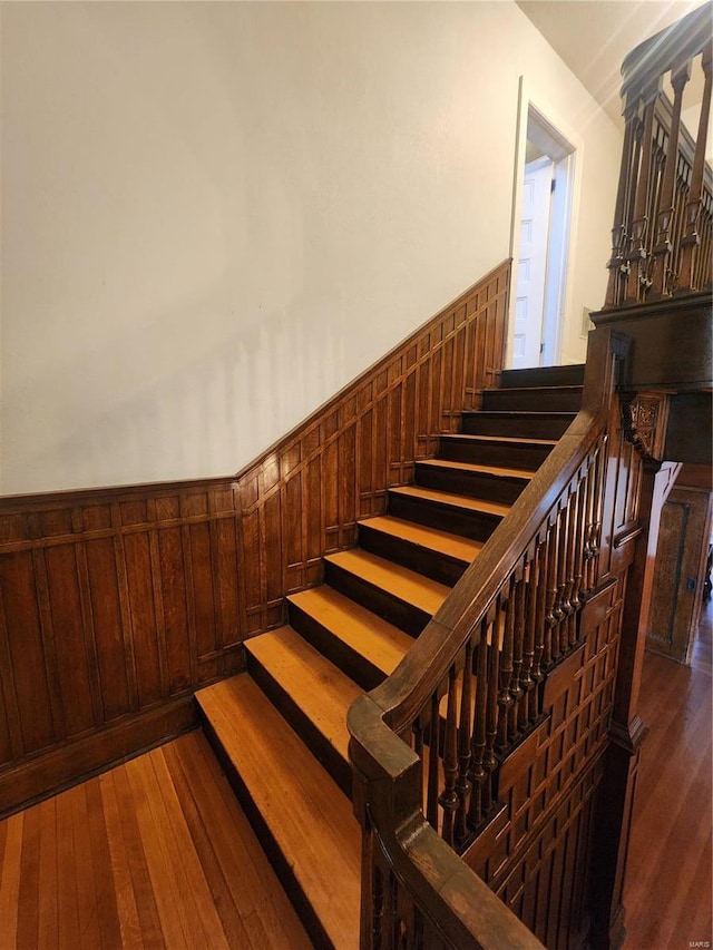 stairway with hardwood / wood-style flooring and wooden walls