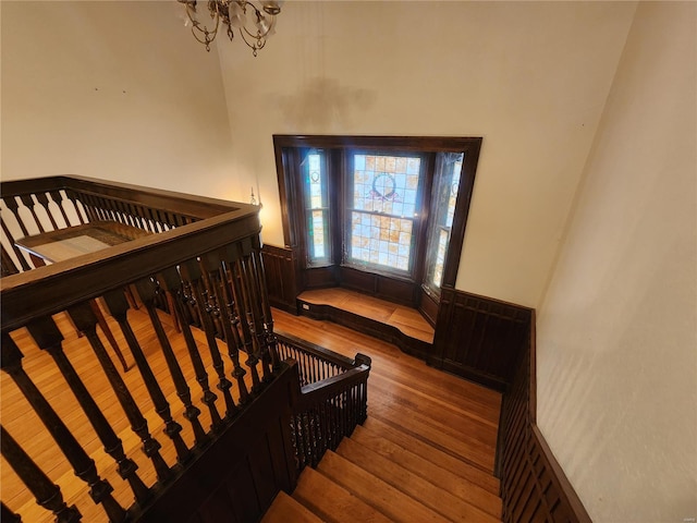 stairs with hardwood / wood-style flooring and an inviting chandelier