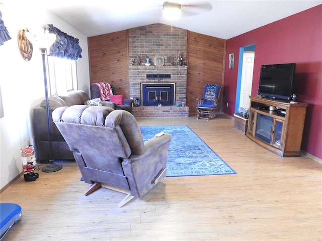 living room with wood walls, light hardwood / wood-style floors, lofted ceiling, and ceiling fan