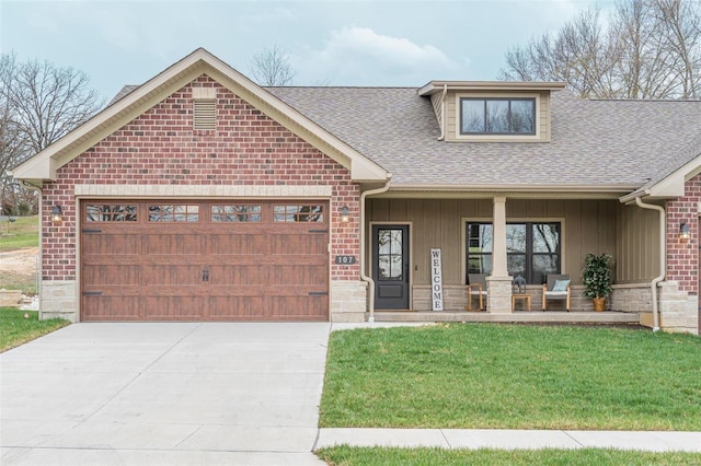 view of front of property featuring a front yard, a garage, and covered porch