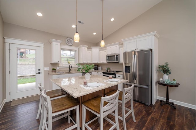 kitchen with stainless steel appliances, white cabinetry, decorative light fixtures, dark hardwood / wood-style flooring, and lofted ceiling