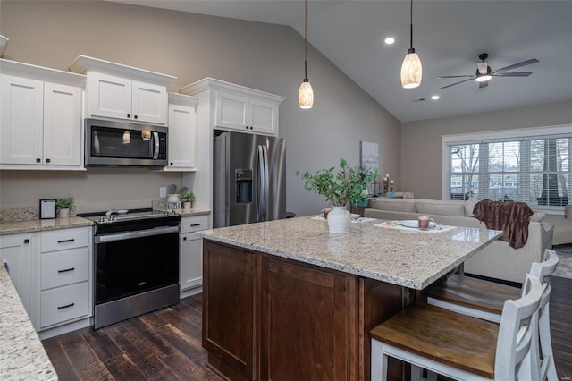 kitchen featuring lofted ceiling, dark wood-type flooring, white cabinetry, appliances with stainless steel finishes, and decorative light fixtures