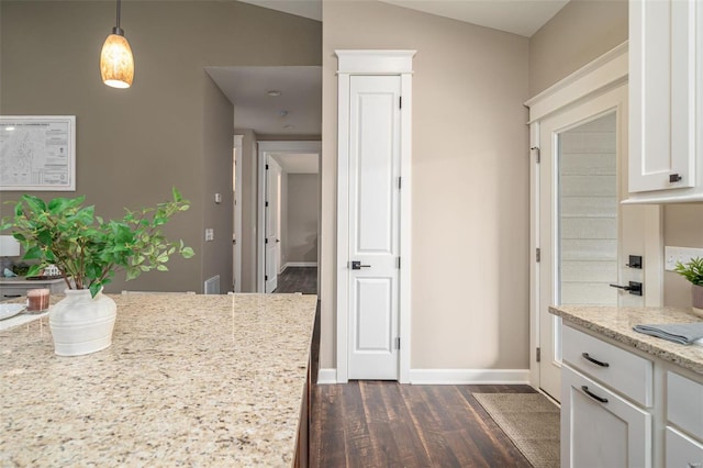 kitchen featuring white cabinetry, light stone countertops, decorative light fixtures, dark hardwood / wood-style flooring, and vaulted ceiling