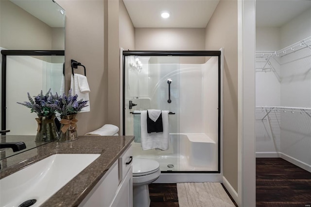 bathroom with hardwood / wood-style floors, a shower with door, vanity, and toilet