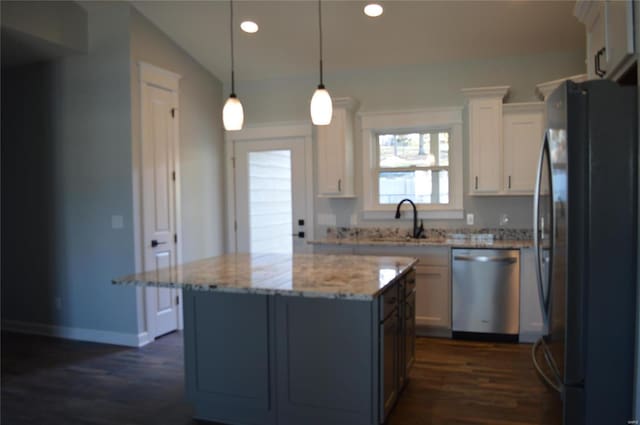 kitchen with black fridge, white cabinetry, decorative light fixtures, vaulted ceiling, and stainless steel dishwasher