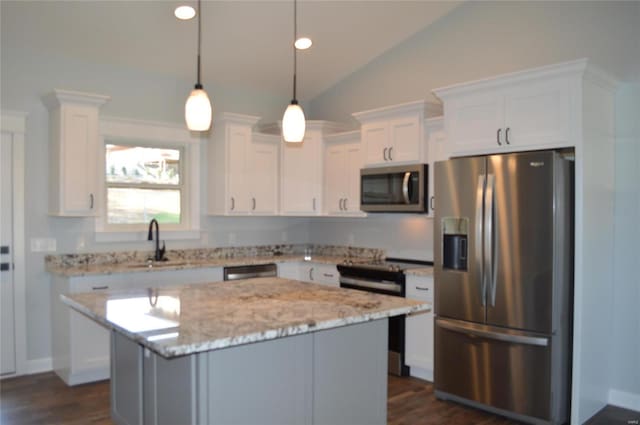 kitchen with stainless steel appliances, white cabinetry, sink, decorative light fixtures, and vaulted ceiling