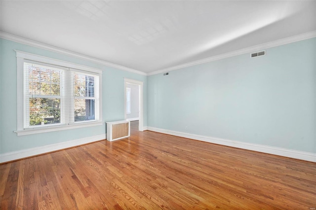 spare room featuring light hardwood / wood-style flooring, crown molding, and radiator