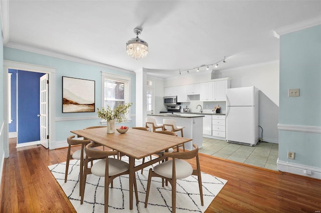 dining room featuring light hardwood / wood-style floors, sink, and crown molding