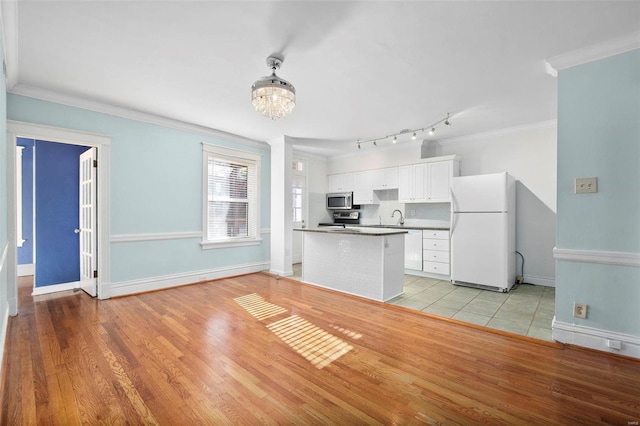 kitchen featuring white cabinetry, light wood-type flooring, appliances with stainless steel finishes, and ornamental molding