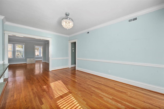 spare room featuring ornamental molding, hardwood / wood-style floors, and a chandelier