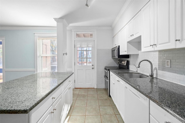 kitchen with white cabinetry, stainless steel appliances, sink, and dark stone countertops