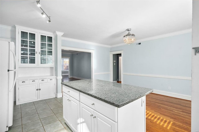 kitchen featuring white cabinetry, crown molding, a center island, white fridge, and light wood-type flooring