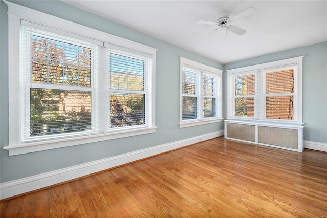 unfurnished sunroom with ceiling fan and radiator