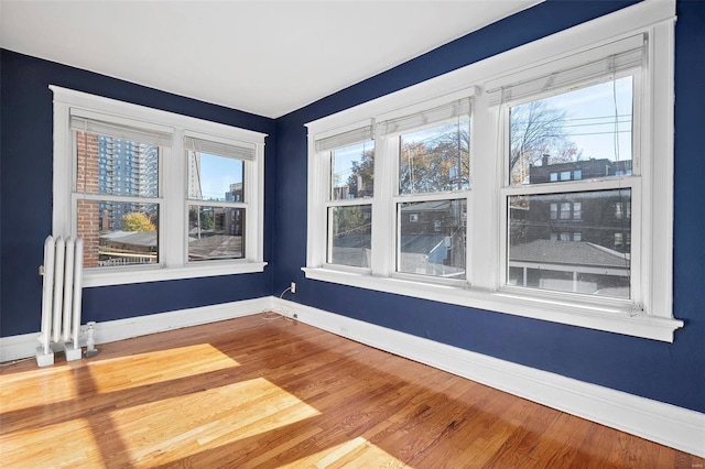 unfurnished room with hardwood / wood-style floors and radiator